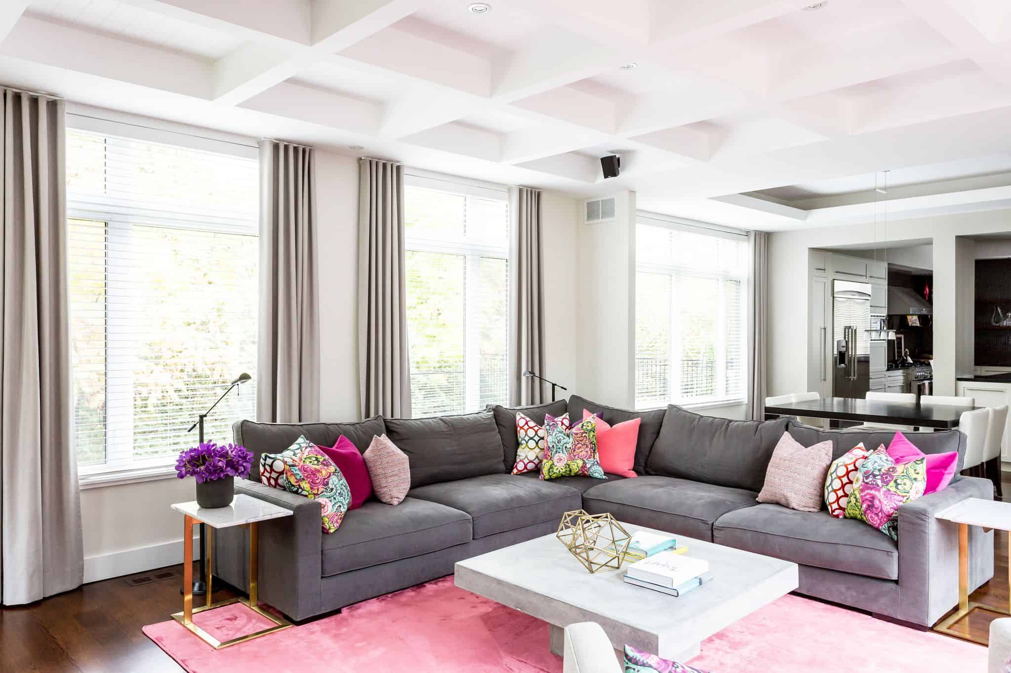Gray corner couch inside a living room with a pink carpet