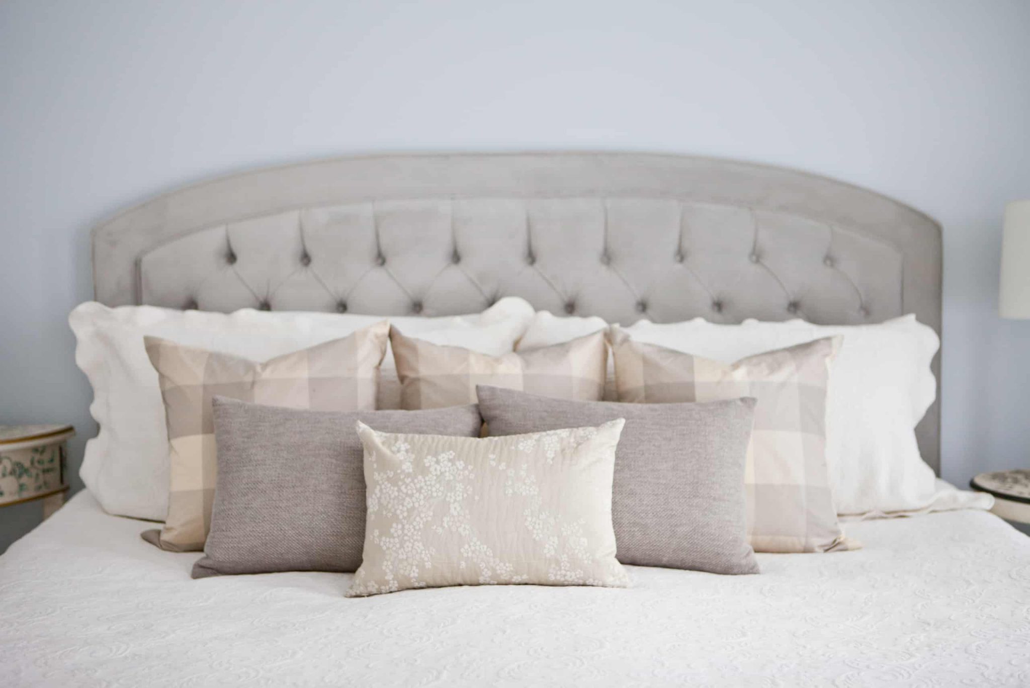 Array of grey and gold pillows on a large white bed